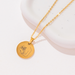 [main] A gold  pendant necklace with a gold chain featuring a mother breastfeeding her child. 